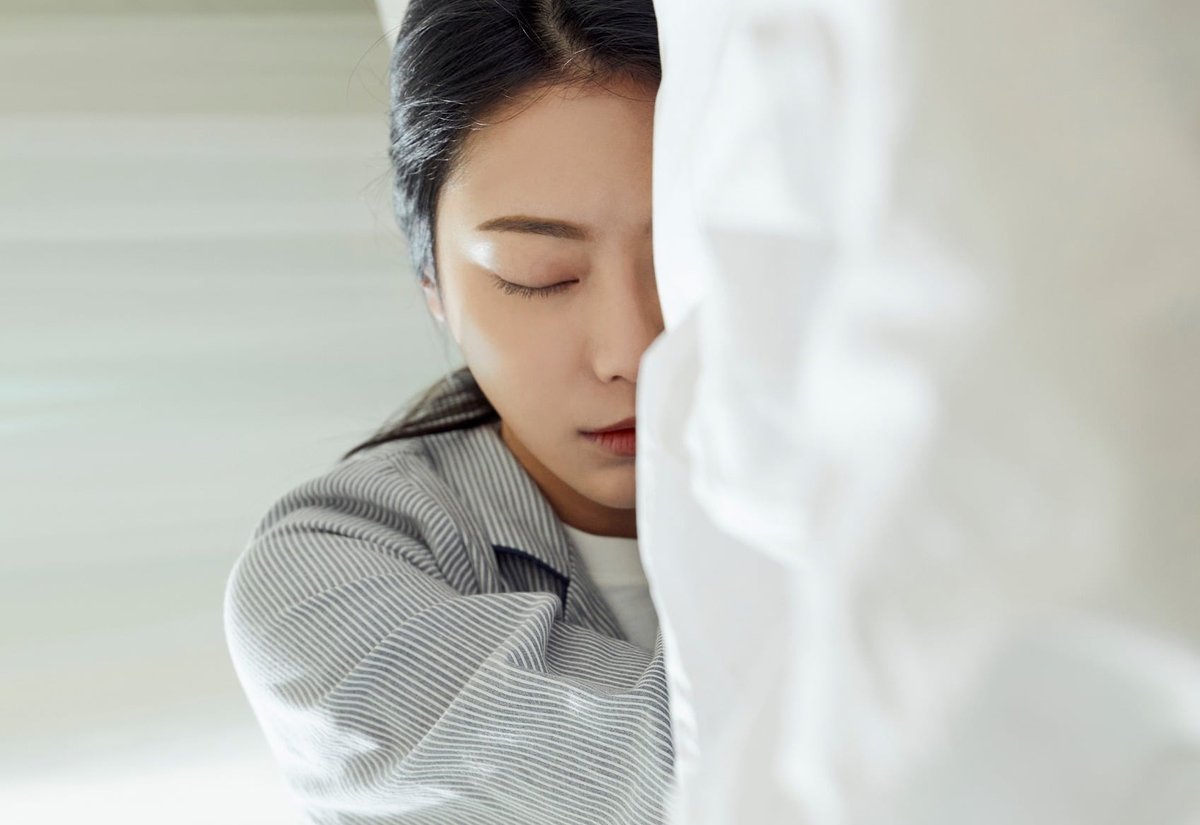 이불을 끌어안고 웅크린 채 누워 있는 여성