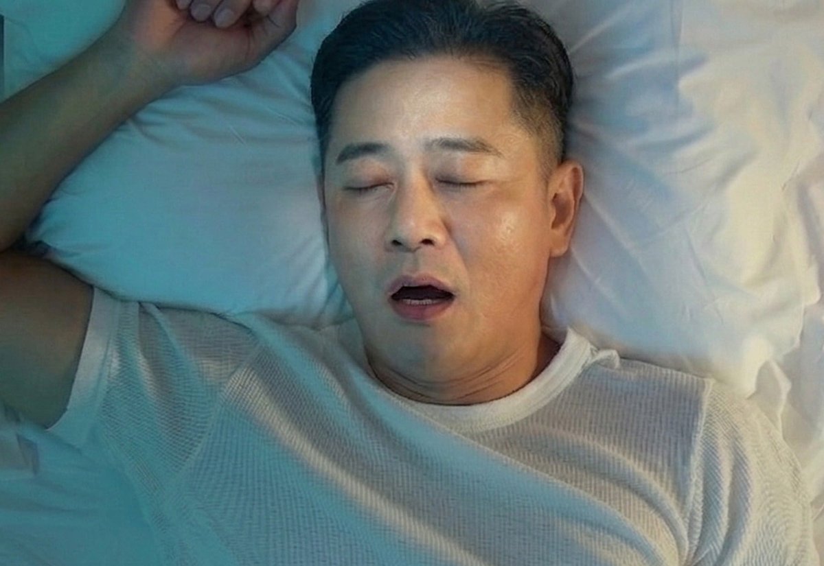침대에서 피곤한 표정으로 하품하는 남성