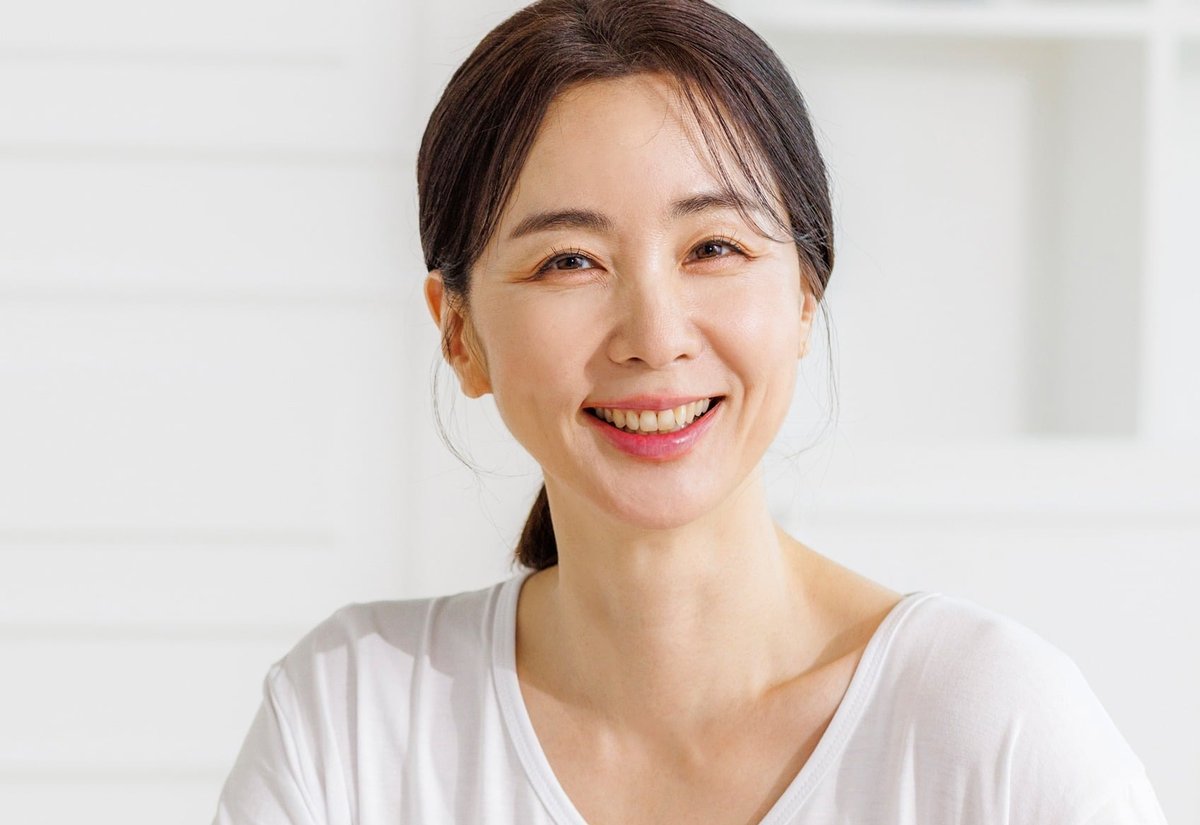 흰 티셔츠를 입고 식탁에 앉아 웃고 있는 여성
