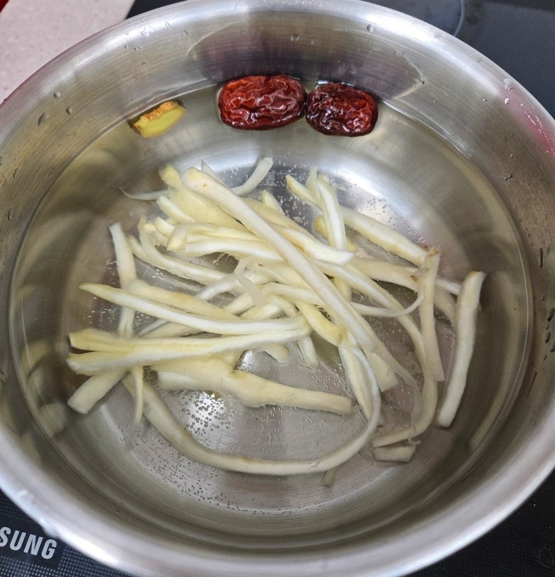 냄비 물에 담긴 채 썬 도라지, 대추 2개, 생강 한 쪽