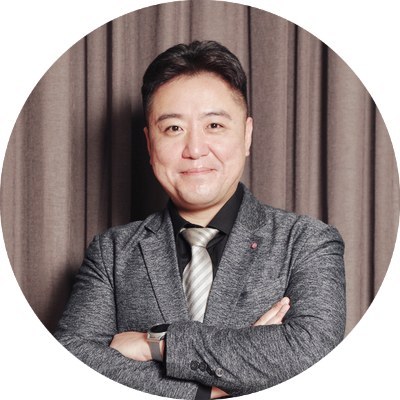 팔짱을 끼고 웃는 정장 차림 남성의 원형 프로필 사진