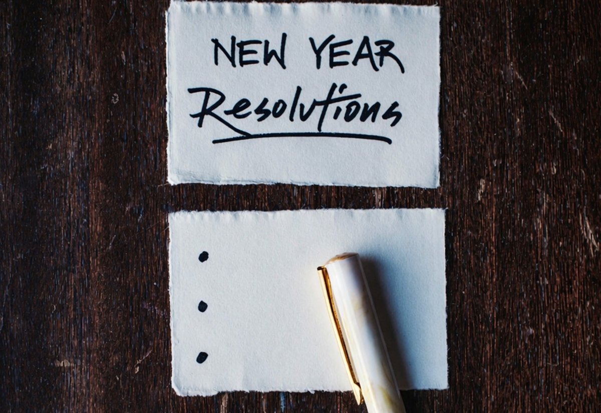 ‘NEW YEAR Resolutions’라고 쓴 종이 카드와 점 세 개가 그려진 카드 위에 놓인 펜