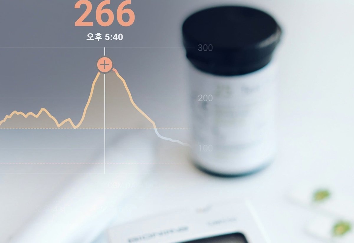 혈당 그래프가 겹쳐진 화면 아래 5.6 mmol/L을 표시한 혈당 측정기와 시험지 통
