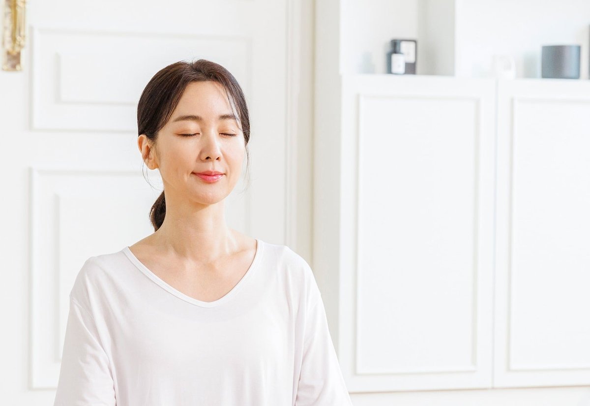 흰 옷을 입고 눈을 감은 채 명상하는 여성